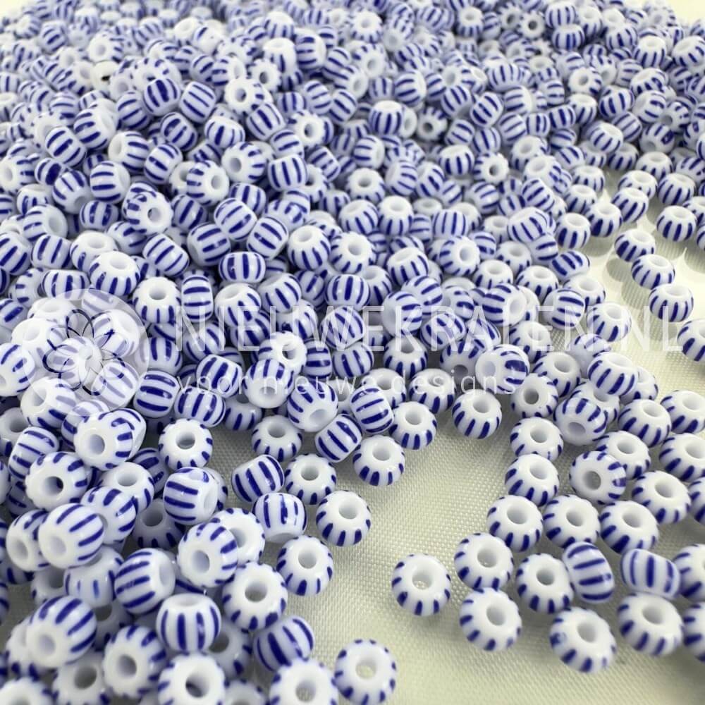 Gestreepte rocailles 6/0 (4 mm) in wit met blauwe strepen, Tsjechische glaskralen van Preciosa; losse kralen op achtergrond.