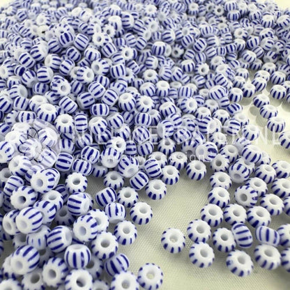 Gestreepte rocailles 6/0 (4 mm) in wit met blauwe strepen, Tsjechische glaskralen van Preciosa; losse kralen op achtergrond.