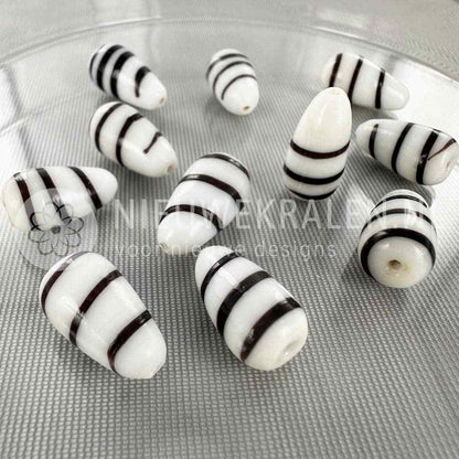 Kromanti druppel glaskralen wit-zwart 17×10mm – handgemaakte glaskralen, elke kraal is uniek en perfect voor Surinaamse sieraden.